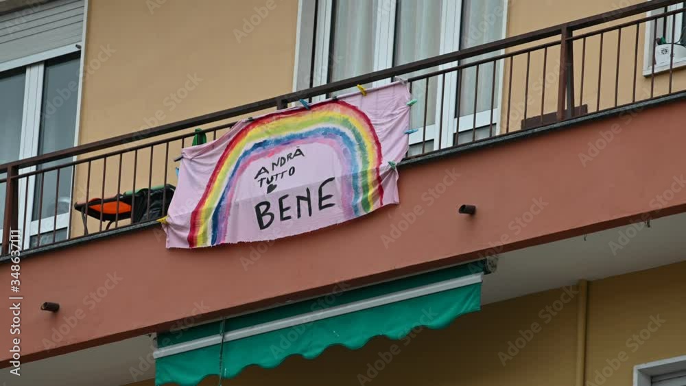 Turin, Piedmont, Italy. May 2020. Coronavirus pandemic. On the facades of the houses hang the sheets with the drawing of the rainbow and message everything will be fine. In Italian 