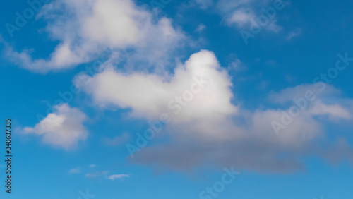 Sky with clouds. Lush, large Cumulus clouds in a clear blue sky illuminated by the rays of the sun on a Sunny day. Realistic sky background. Template. 