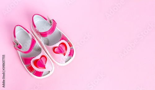 Children's shoes with a red heart. Isolated on pink background. Copy space.
