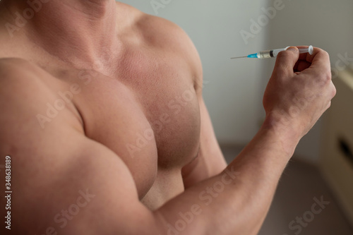 Close-up of a naked male torso. Unrecognizable shirtless bodybuilder man puts himself an injection of testosterone. Faceless athlete takes dope.
