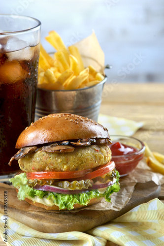 vegan Burger with fries and a glass of cola on a light background
