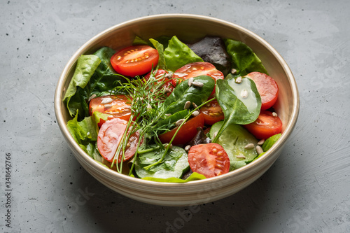 Salad of fresh tomato, spinach, fennel, lettuce on a gray blackground .Healthy tasty food, homemade concept. 