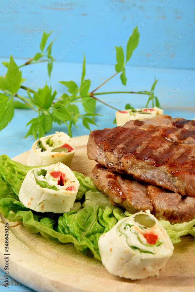 Sliced tortilla with vegetables next to fried grilled steak Sliced tortilla with vegetables next to fried grilled steak