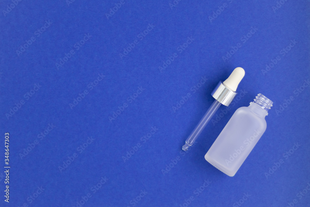 Naklejka premium Butelka na nawilżające serum kolagenowe z hialuronem na tle indygo. Kolor roku.