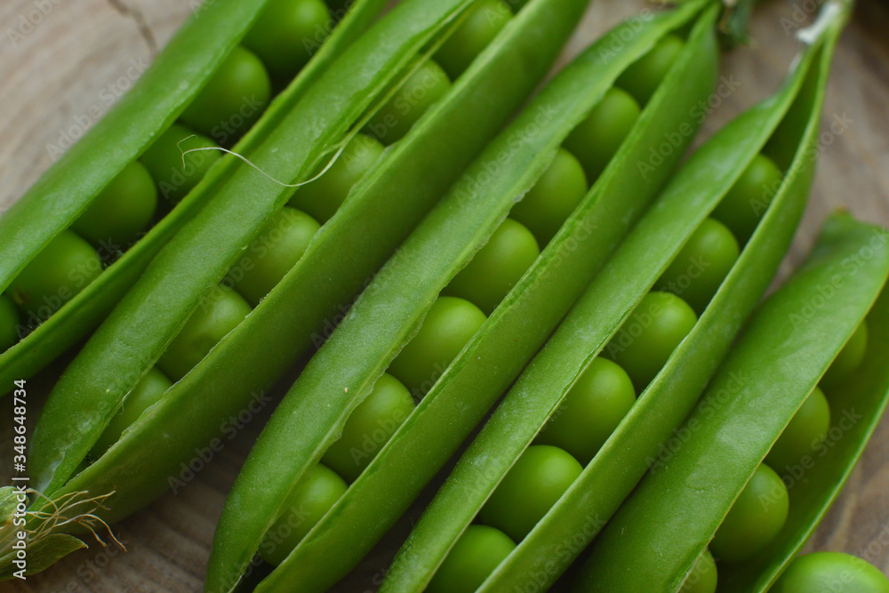New harvest of fresh ripe green peas. legumes.Green peas and pea pods on wooden background.Close-up New harvest of fresh ripe green peas. legumes.Green peas and pea pods on wooden background.Close-up