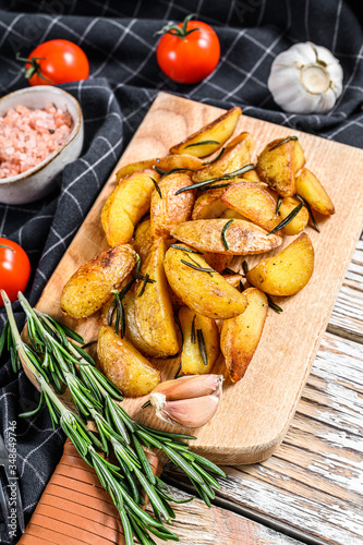 Roasted potato wedges with rosemary and salt. Tasty spicy potato. White background. Top view