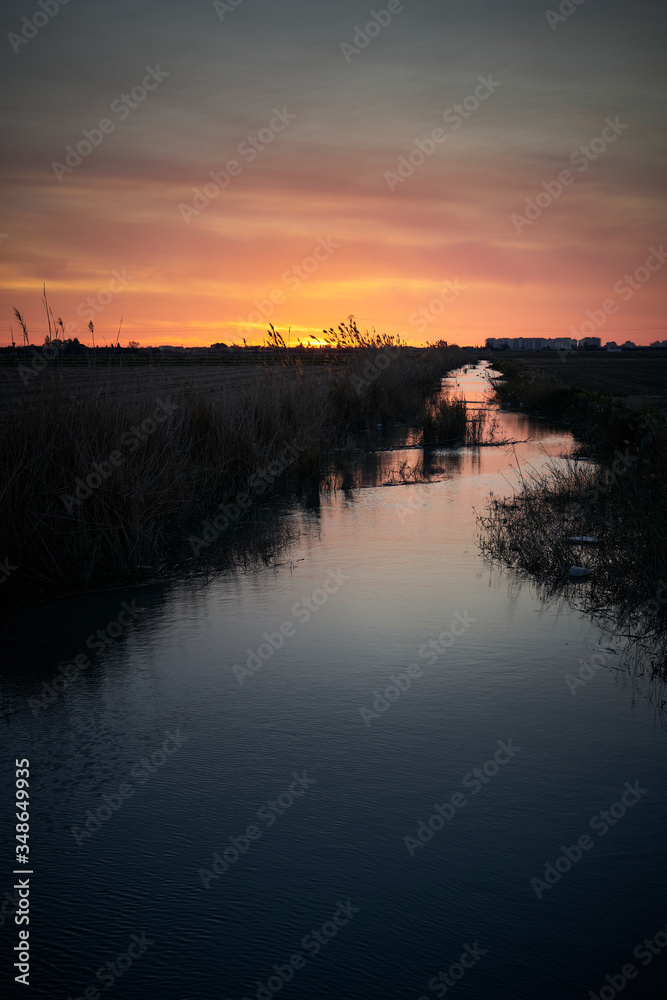Breathtaking shot of a spanish polder in a field and the rising sun in the background