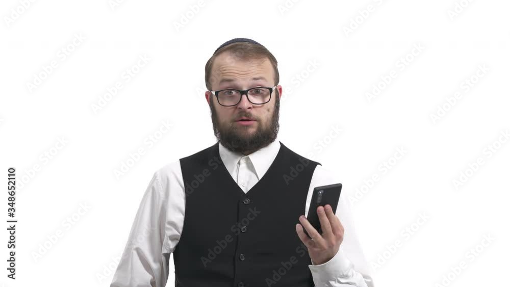 Portrait of a young male Jew with a smartphone in his hands, looking at the screen and expressing surprised emotions. Shocked man uses his gadget. Isolated, on white background Portrait of a young male Jew with a smartphone in his hands, looking at the screen and expressing surprised emotions. Shocked man uses his gadget. Isolated, on white background