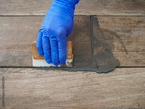 Wallpaper Mural Grouting between ceramic tiles. A hand in a blue glove holds a spatula. Repair in the room Torontodigital.ca