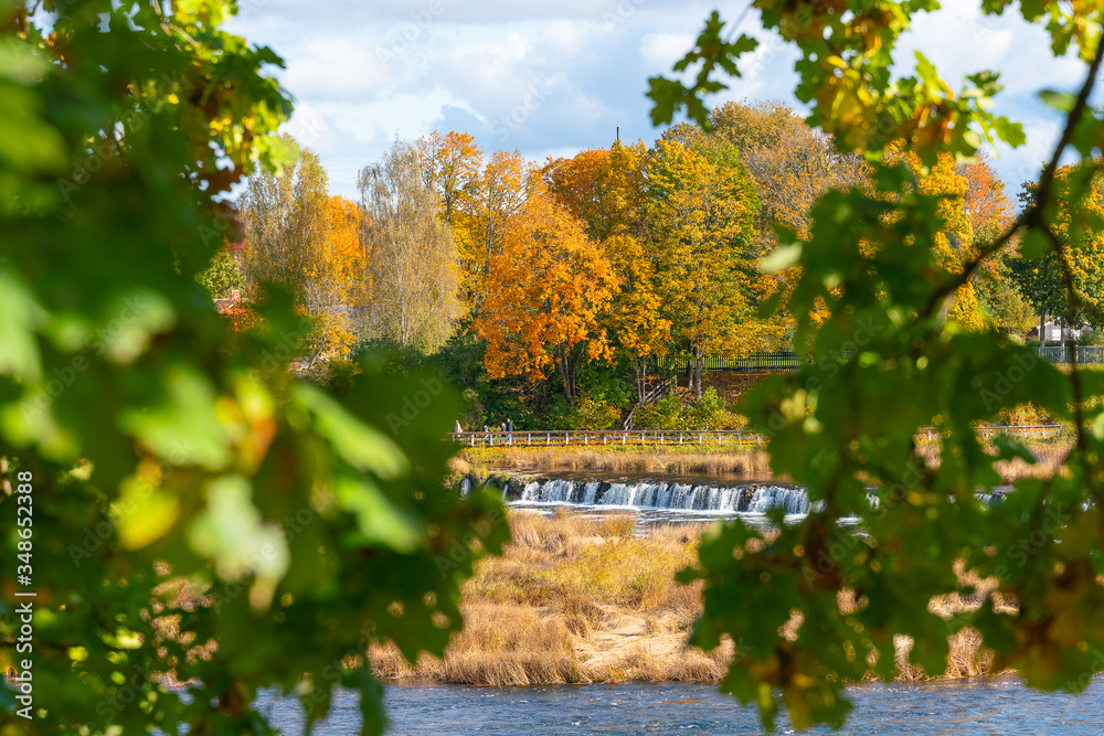 Obraz premium View of the Rumba waterfall in Kuldiga in the fall. Colorful leaves. Beautiful landscape in Latvia.