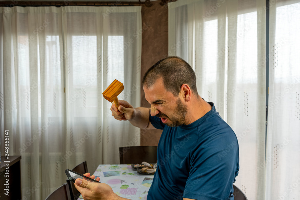 Fototapeta premium Furious man with a beard and short hair in a navy blue shirt throwing his mobile
