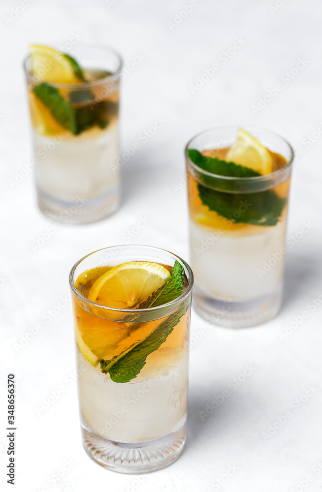 tea with ice, mint and lemon wedges on white table tea with ice, mint and lemon wedges on white table