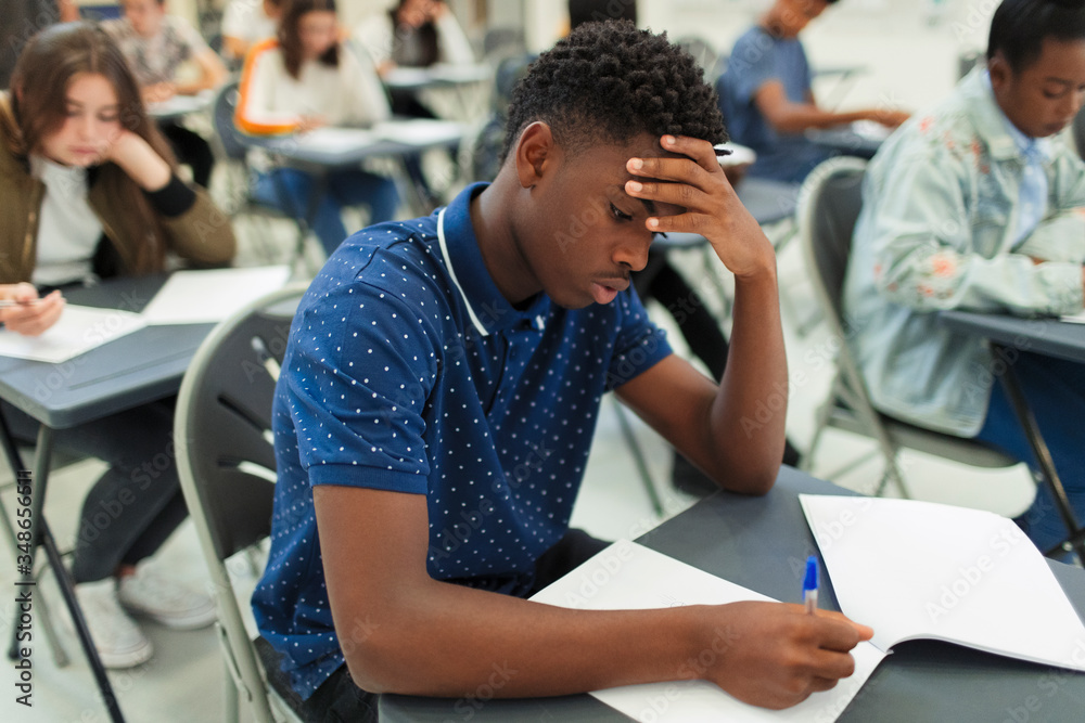 © Paul Bradbury/Caia Image - Focused high school boy taking exam at desk in classroom © Paul Bradbury/Caia Image - Focused high school boy taking exam at desk in classroom