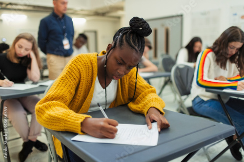 Focused high school girl student taking exam at desk
