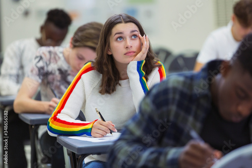 Focused high school girl student taking exam looking up photo