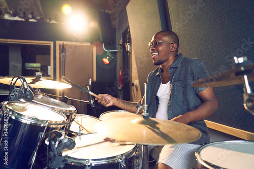 Male musician playing drums in recording studio photo