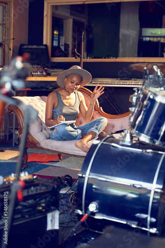 Female musician song writing in recording studio
