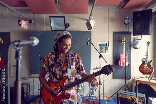 Male musician playing electric guitar in recording studio