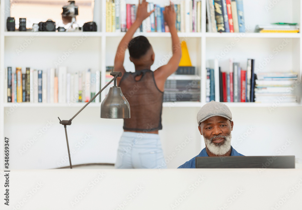 © Paul Bradbury/Caia Image - Father using computer and daughter at bookcase in home office