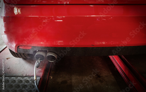 Equipment connected to exhaust pipe on car in auto repair shop