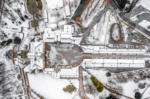 Aeril overhead view of Schloss Hellbrunn covered in snow with view of Untersberg near Salzburg Outskirts in winter time © Davidzfr