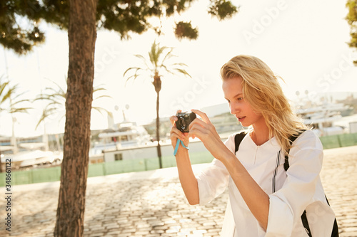 A girl making photos in Barcelona in the sun with palms