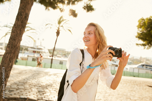 A girl making photos in Barcelona in the sun with palms