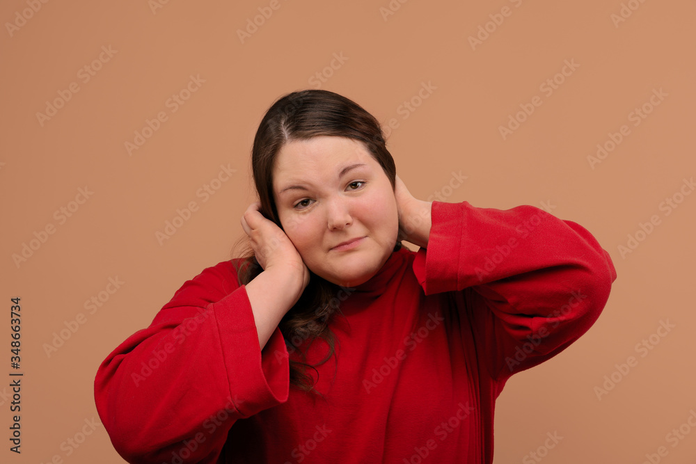 The upset girl covered her ears with her hands. An overweight girl. The upset girl covered her ears with her hands. An overweight girl.