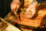 Beekeeper at work. Inspection by a beekeeper of a beehive with bees. Close up of beekeeper's hands. Using a beekeeping tool to pick up honey comb in wooden frame.