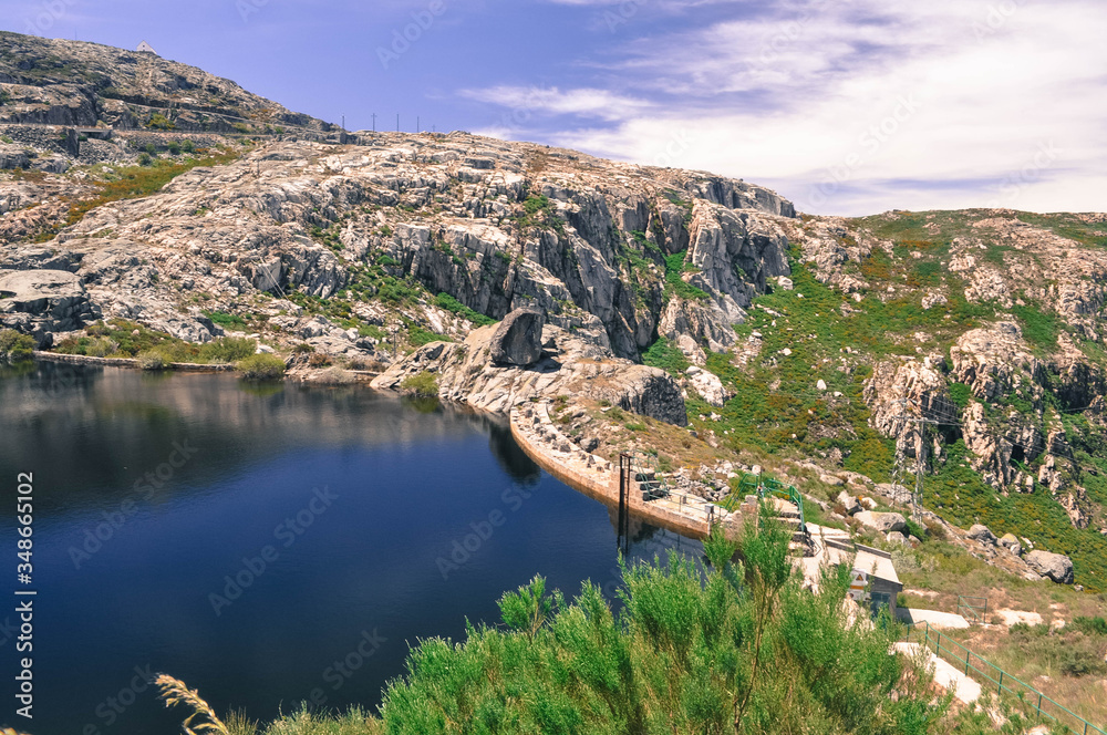 Mountain lake with cliffs around the overgrown grass. Blue Sky