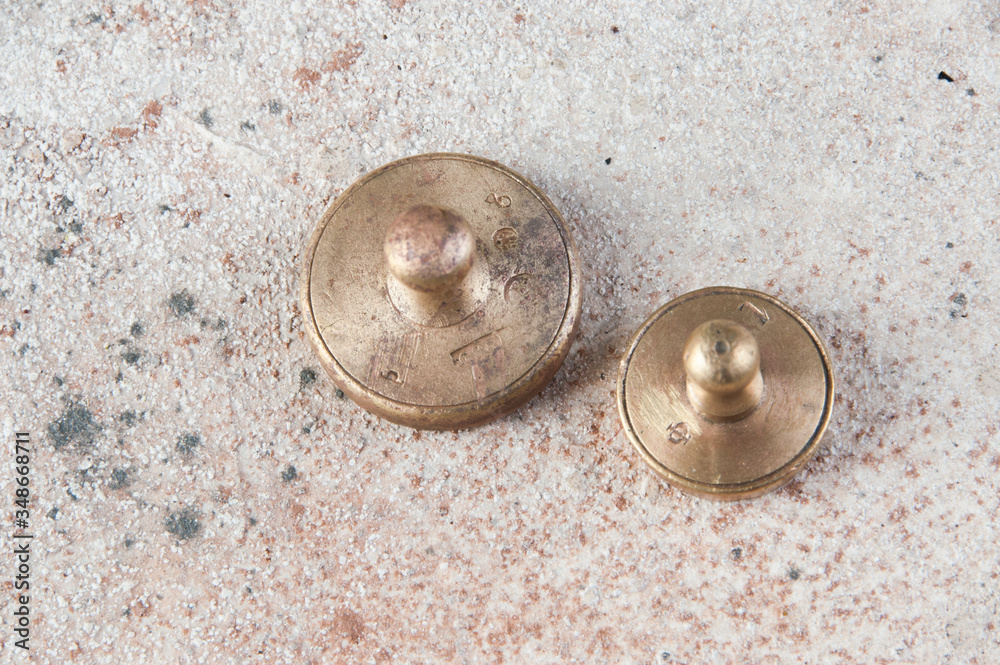 Two antique bronze weights for scales on concrete background. Two antique bronze weights for scales on concrete background.