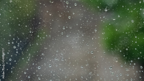 Raindrops on the window. Blur background of the street road and trees