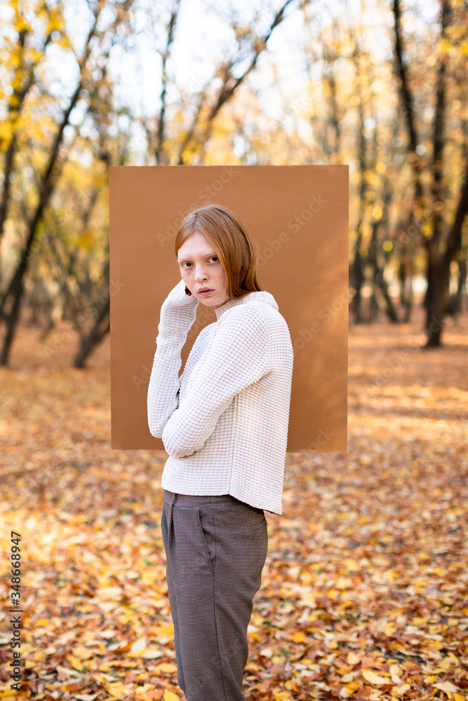 Young model demonstrating everyday fashion against small carton square on background of autumn park Young model demonstrating everyday fashion against small carton square on background of autumn park