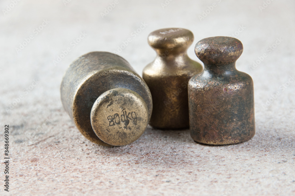 Three antique bronze weights for scales on concrete background.