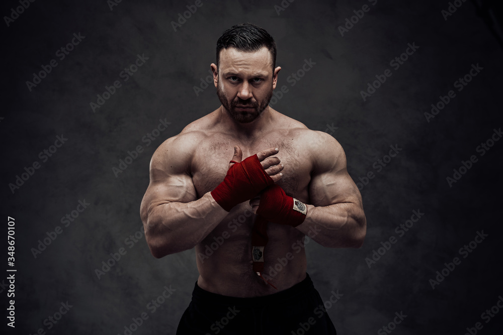 Healthy and energetic man wrapping his wrist bands on his hands, focused and looking strong