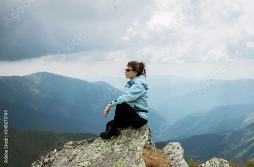 Gilr sitting on a high mountain. Freedom, traveling, hiking and trekking concept.