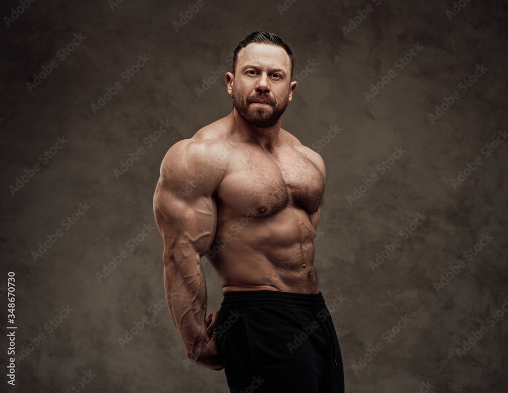 Strong sportsman posing in a studio while showing his triceps and abdominal muscles