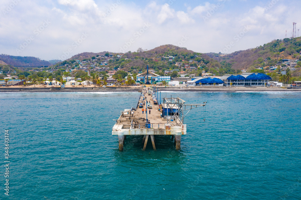 Frontal aerial view of the port of La Libertad, without any people, boats lined up on the dock and the green mountains of the coast El Salvador.