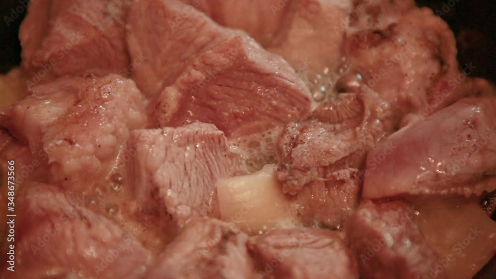 Chunks of red juicy meat are fried in a pan close-up. Chunks of red juicy meat are fried in a pan close-up.