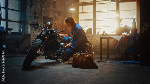 Young Beautiful Female Mechanic Comes to Garage and Starts Working on a Custom Motorcycle. Talented Girl Wearing a Blue Jumpsuit. She Uses a Spanner to Tighten Nut Bolts. Creative Authentic Workshop.