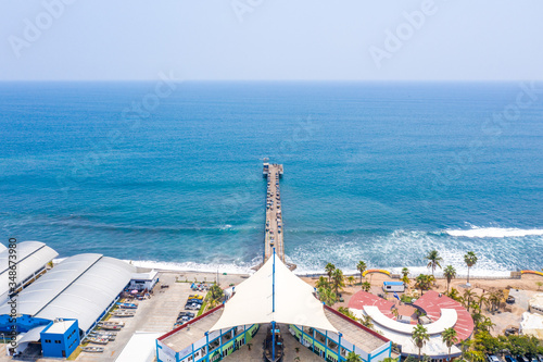 Aerial view over the coastal area on La Libertad beach in El Salvador, where you can see in its entirety its pier and the turquoise sea water.