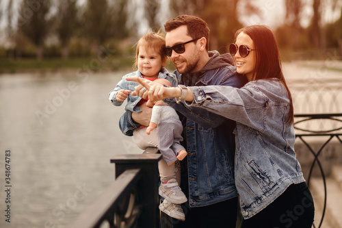 family walk, father and mother hold daughter in their arms, family walks by the river photo