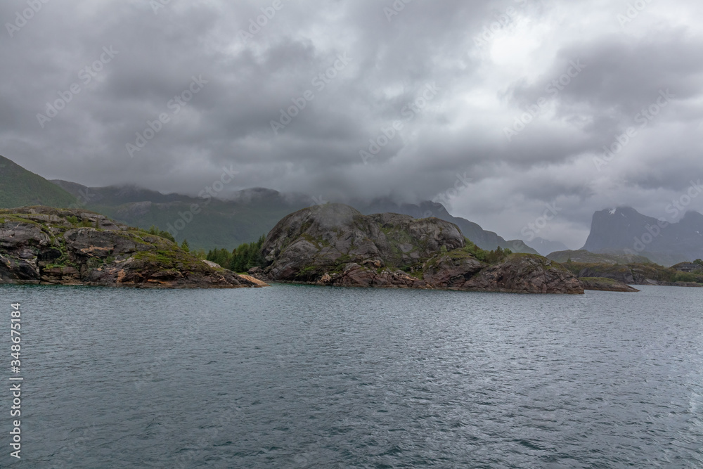 A mystical fjord in Norway with mountains and fog hanging over the water in polar day. midnight sun, selective focus