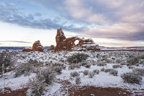 Turret Arch at Arches National Park in snow when sun is rising.