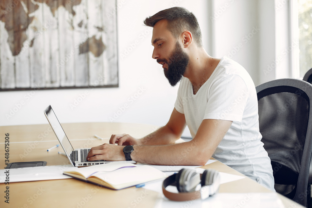 Students create a new project. Guy learning and use the laptop. Man in a white t-shirt Students create a new project. Guy learning and use the laptop. Man in a white t-shirt