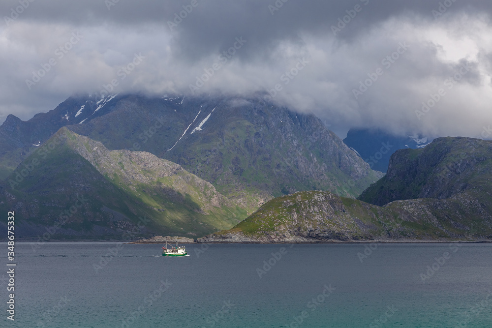 ship to visit fjords in Norway in polar day, midnight sun. A mystical fjord with dark clouds in Norway with mountains and fog hanging over the water