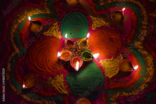Oil lamps lit on colorful rangoli during diwali celebration in India