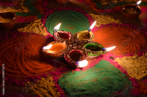 Oil lamps lit on colorful rangoli during diwali celebration India