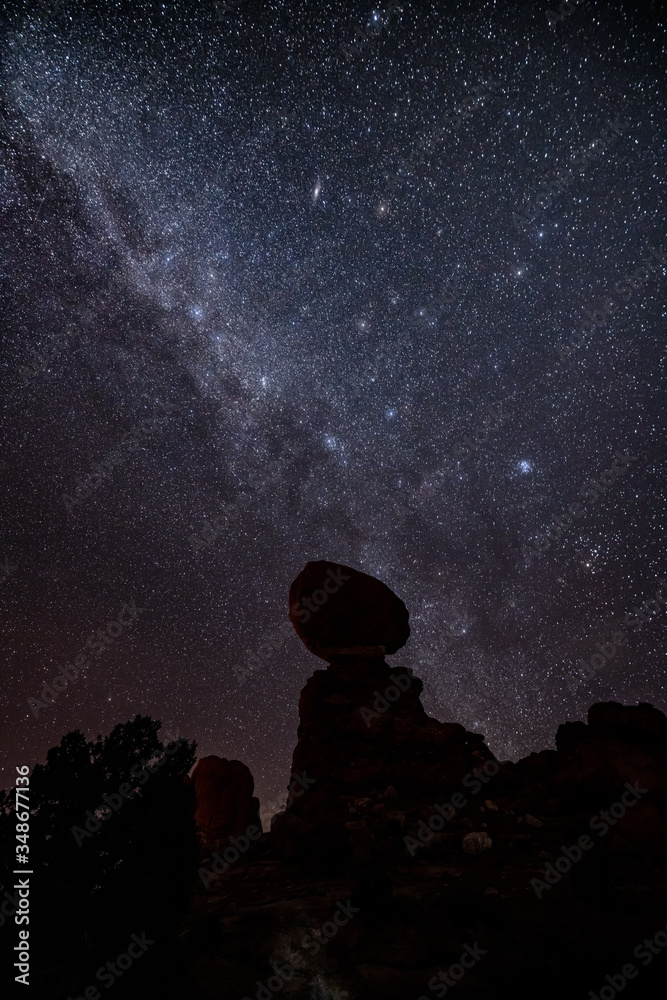 Night sky and Milky Way behind Balanced Rock at Arches National Park after sunset.