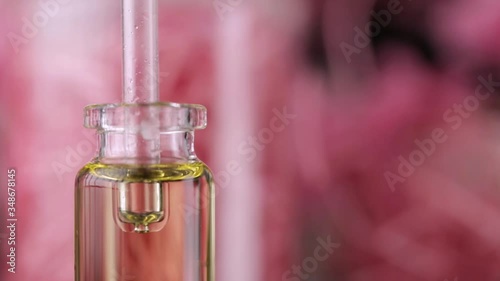 Blend of essential oils closeup. Making some aroma liquids, perfume. Drops falling from pippet to little glass bottle. Slowmotion. Liquid ingredients, body care production, cosmetology. photo